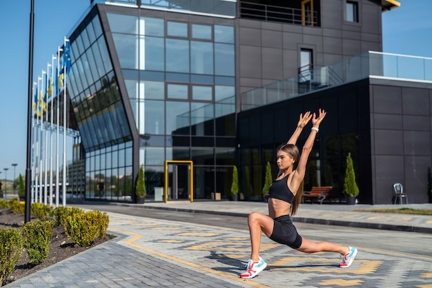 Jonge fitness vrouw doet stretching yoga-oefeningen in de buurt van modern stadsgebouw. gezonde levensstijl