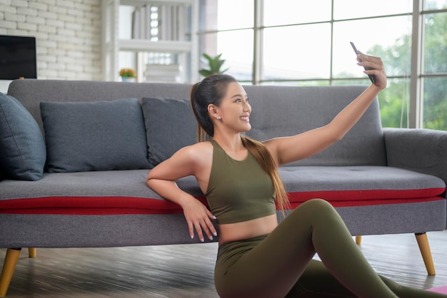 Jonge fitness vrouw in sportkleding met behulp van slimme telefoon tijdens het sporten thuis Gezond en levensstijl