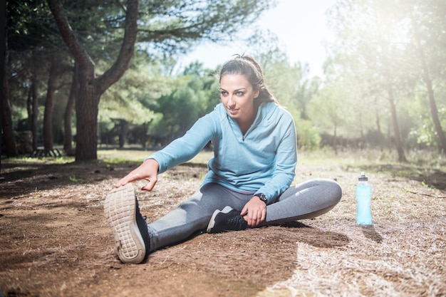 Jonge fitness vrouw loper benen uitrekken voordat rennen in het park