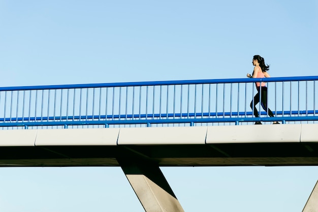 Jonge fitness vrouw loper draait op stadsbrug. Sportconcept.