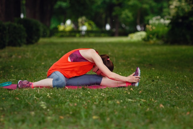 Jonge fitness vrouw loper strekken en opwarmen van de benen voor het uitvoeren van het idee en het concept van een gezonde levensstijl die zich voorbereidt op lichamelijke inspanning Groen park Zomermiddag