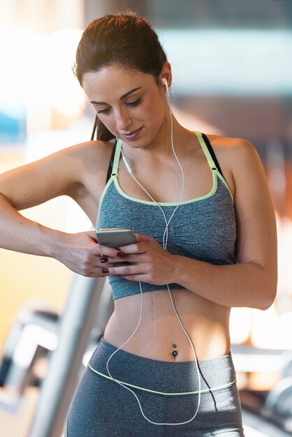 Foto jonge fitness vrouw op zoek naar telefoon op sportschool. sportconcept.