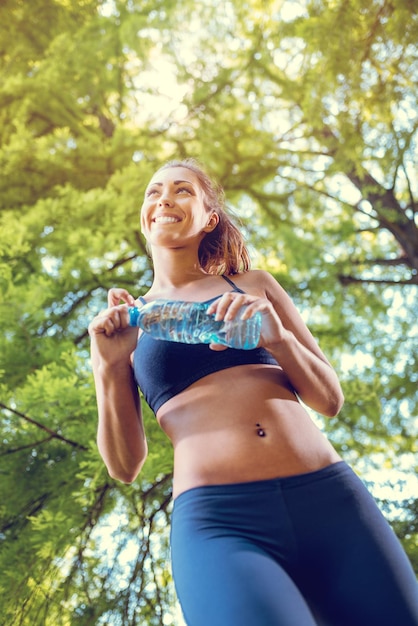 Jonge fitness vrouw rust na een zware training in het stadspark. Kijk van onderaf.