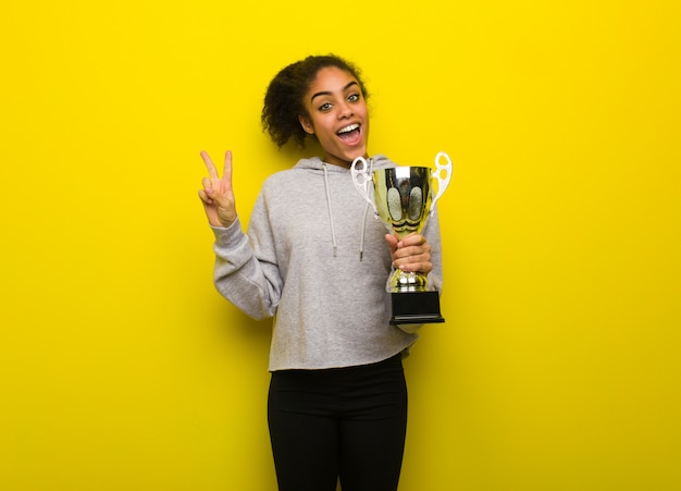 Foto jonge fitness zwarte vrouw doet een gebaar van overwinning