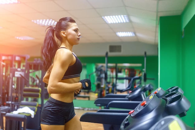 Jonge fitnessvrouw die cardio-oefeningen doet in de sportschool die op een loopband loopt, vrouwelijke hardloper die traint op de gim