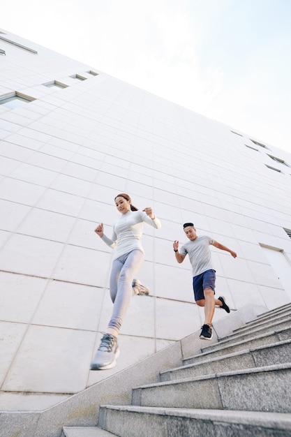 Jonge fitte Vietnamese man en vrouw rennen buiten de trap af tijdens het trainen voor de marathon