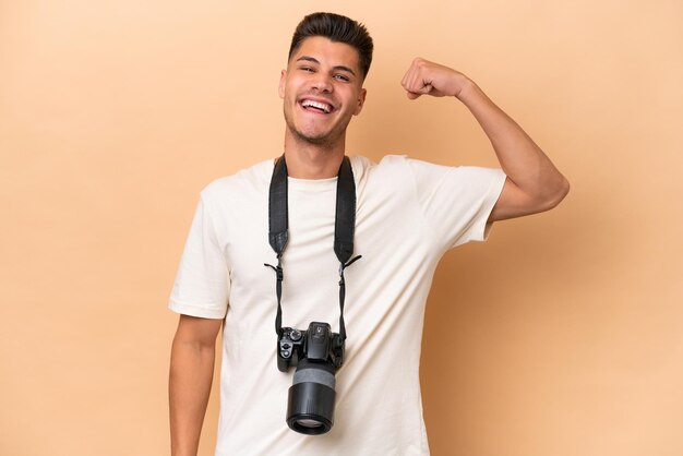 Jonge fotograaf blanke man geïsoleerd op beige achtergrond die sterk gebaar doet