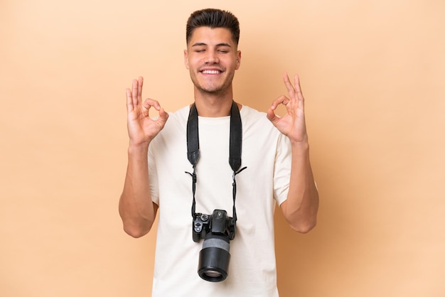 Foto jonge fotograaf blanke man geïsoleerd op beige achtergrond in zen pose