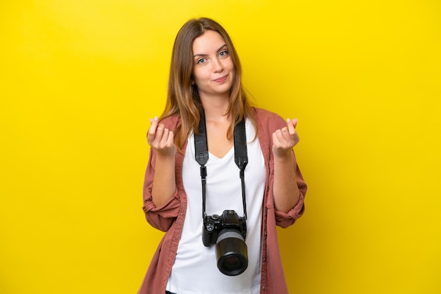 Jonge fotograaf blanke vrouw geïsoleerd op gele achtergrond geld gebaar maken