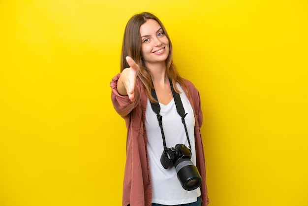 Jonge fotograaf blanke vrouw geïsoleerd op gele achtergrond handen schudden voor het sluiten van een goede deal