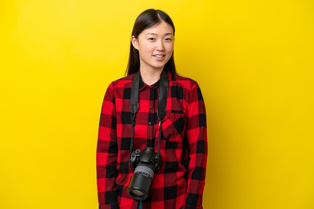 Jonge fotograaf Chinese vrouw geïsoleerd op gele achtergrond lachen