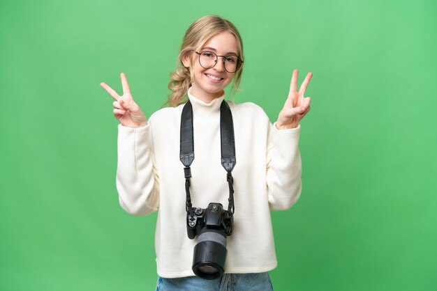 Jonge fotograaf Engelse vrouw over geïsoleerde achtergrond die overwinningsteken met beide handen toont