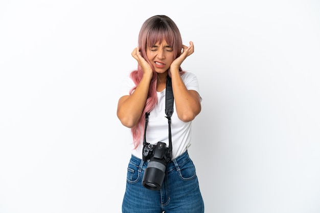 Jonge fotograaf gemengd ras vrouw met roze haar geïsoleerd op een witte achtergrond gefrustreerd en bedekkende oren