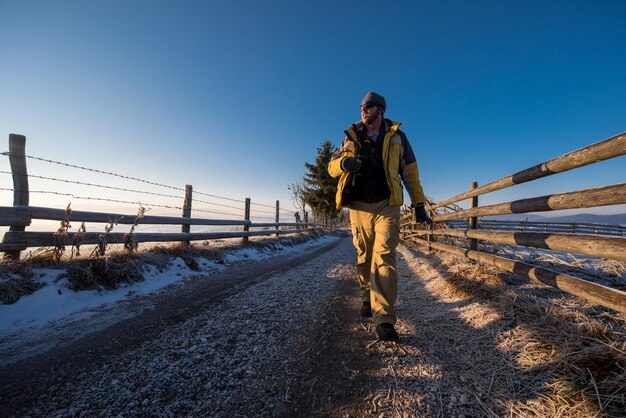 jonge fotograaf geniet van de prachtige natuur tijdens een wandeling op een landweg tijdens een zonnige winterdag