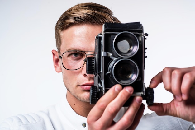 Jonge fotograaf met bril legt beeld vast in het oog van retro camera geïsoleerd op witte shoot