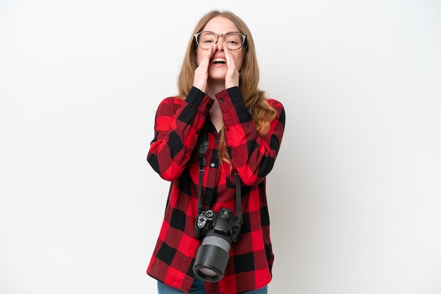 Jonge fotograaf mooie vrouw geïsoleerd op witte achtergrond schreeuwen en iets aankondigen