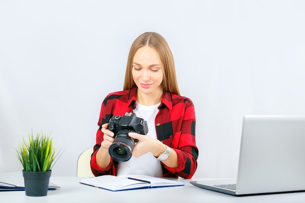 Jonge fotograaf of grafisch ontwerper op het werk op kantoor of thuis. Vrouw die in bureau fotocamera bekijkt.