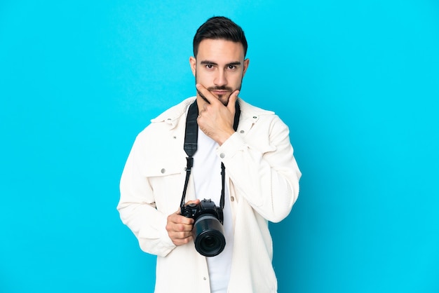 Jonge fotograafmens die bij het blauwe muur denken wordt geïsoleerd