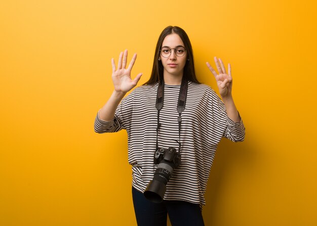 Foto jonge fotograafvrouw die nummer negen toont