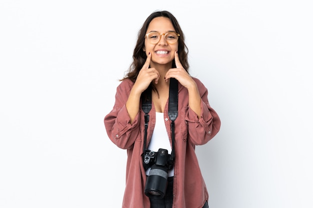 Jonge fotograafvrouw over geïsoleerd wit dat met een gelukkige en prettige uitdrukking glimlacht