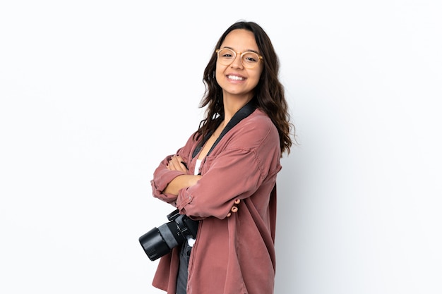 Jonge fotograafvrouw over geïsoleerd wit met gekruiste wapens en vooruit kijkend