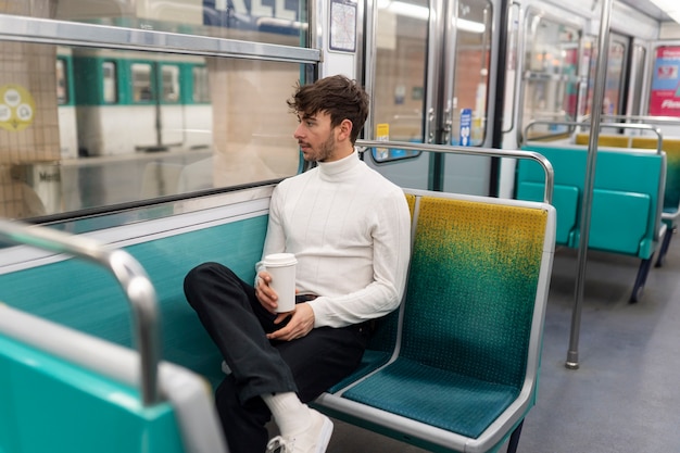 Jonge franse man rijdt in de metro en drinkt koffie