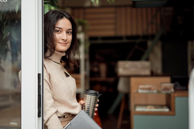 Jonge freelancer leunend op de deuropening van het café