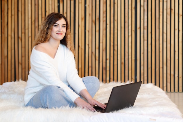 Jonge freelancer-vrouw zit thuis op de bank en gebruikt een laptop