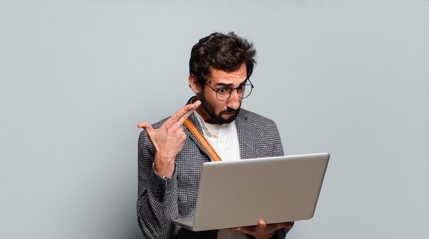 Jonge, gebaarde en gekke zakenman met laptop