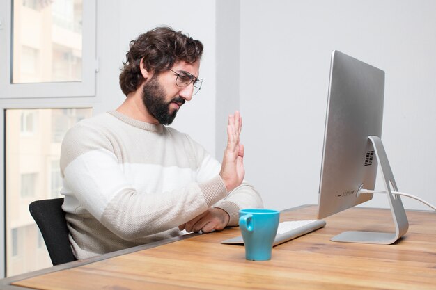 Jonge gebaarde gekke freelancer die met zijn computer werkt