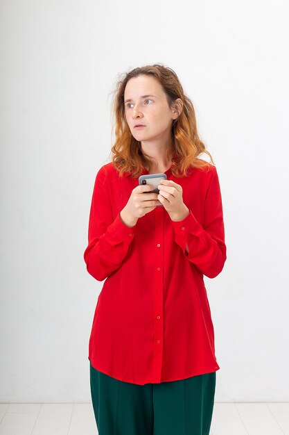 Jonge geconcentreerde blanke roodharige vrouw met behulp van mobiele telefoon, chatten op het web