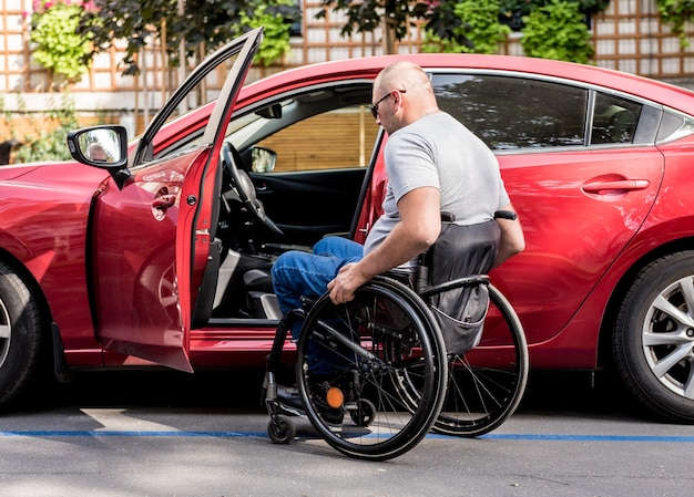 Jonge gehandicapte bestuurder die in rode auto fom rolstoel krijgt