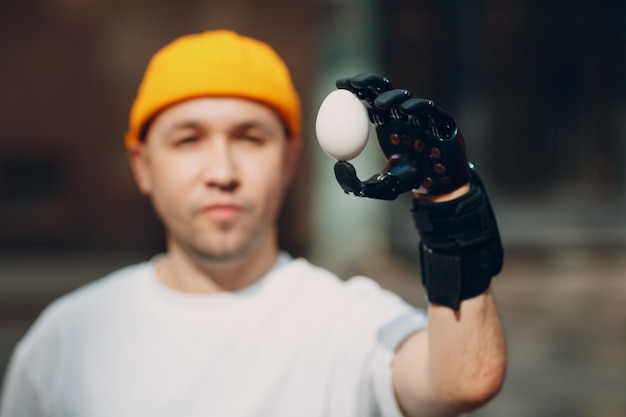 Foto jonge gehandicapte man houdt ei met kunstmatige prothese hand in casual kleding.