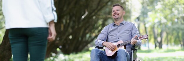 Jonge gehandicapte man in rolstoel zingt lied voor zijn vriendin in het parkconcept van