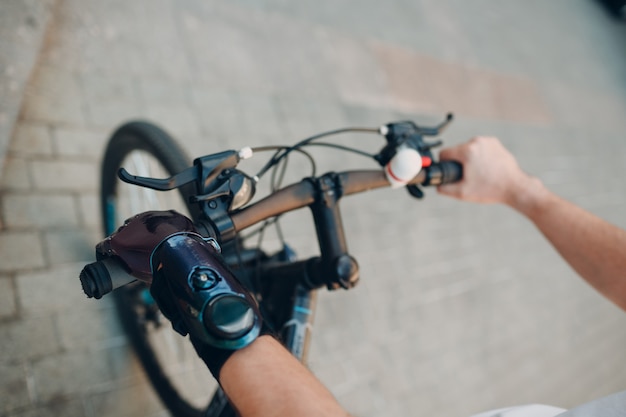 Jonge gehandicapte man met kunstmatige prothese hand in casual kleding op de fiets