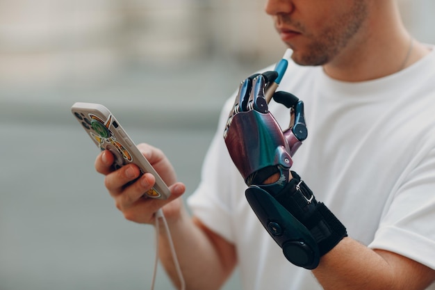 Jonge gehandicapte man rookt elektronische sigaret met kunstmatige prothese hand in vrijetijdskleding