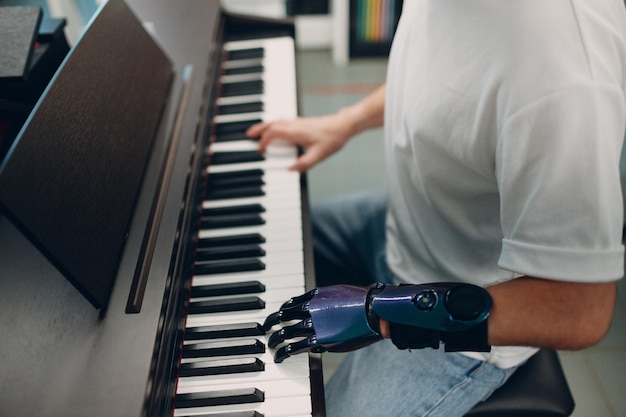 Jonge gehandicapte man speelt op elektronische pianosynthesizer met kunstmatige prothesehand in muziekwinkel