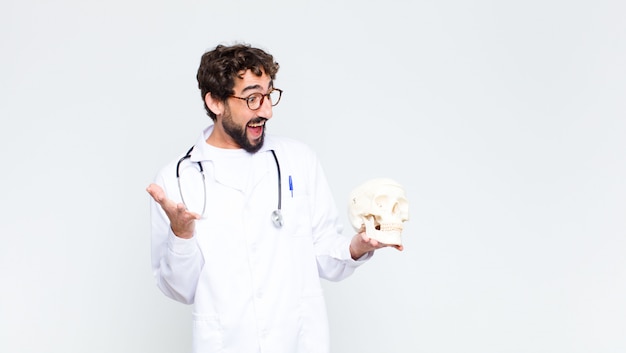 Jonge gekke bebaarde dokter man met een menselijke schedel