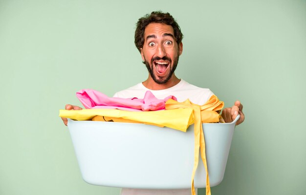 Foto jonge gekke bebaarde en expressieve man met kleren om huishoudsterconcept te wassen