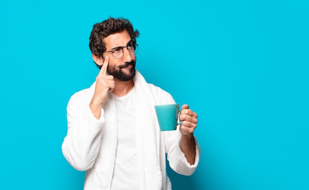 Jonge gekke bebaarde man badjas met een koffiekopje dragen