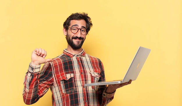 Jonge gekke bebaarde man gelukkige uitdrukking en een laptop