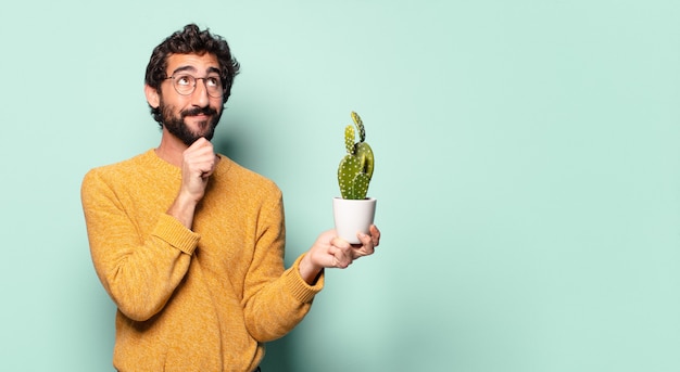 Jonge gekke bebaarde man met een cactus kamerplant