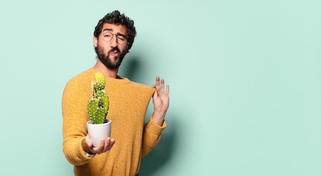 Jonge gekke bebaarde man met een cactus kamerplant