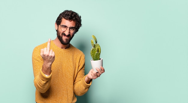 Jonge gekke bebaarde man met een cactus kamerplant