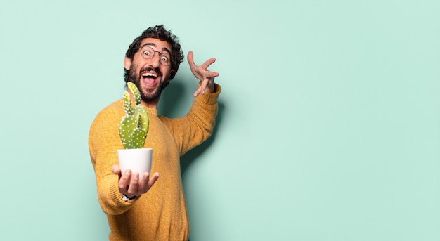 Jonge gekke bebaarde man met een cactus kamerplant