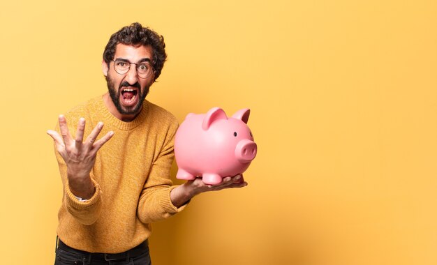 Jonge gekke bebaarde man met een spaarvarken