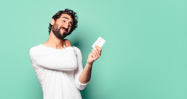 Jonge gekke bebaarde man met een tablet pillen