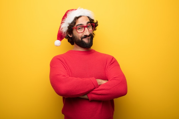 Jonge gekke bebaarde man met rode bril en hoed van de Kerstman