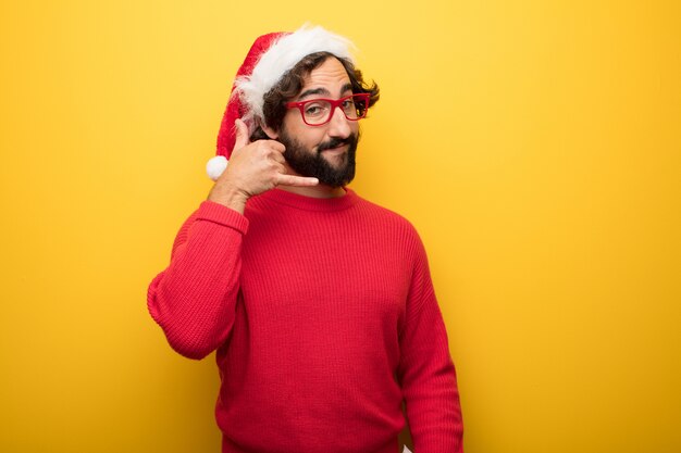 Jonge gekke bebaarde man met rode bril en hoed van de kerstman