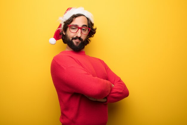 Jonge gekke bebaarde man met rode bril en hoed van de Kerstman